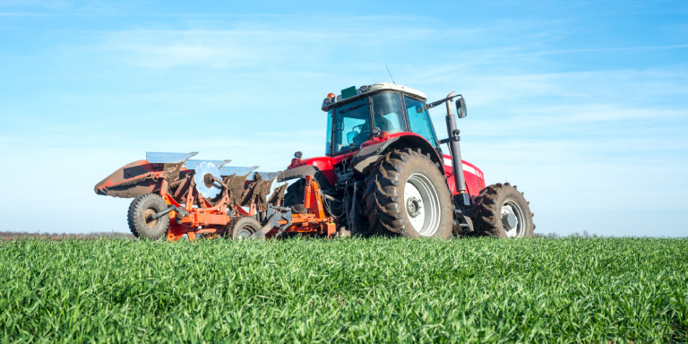 Imagen de tractor agrícola en un campo, mostrando la importancia de elegir las llantas agrícolas adecuadas para los cultivos.